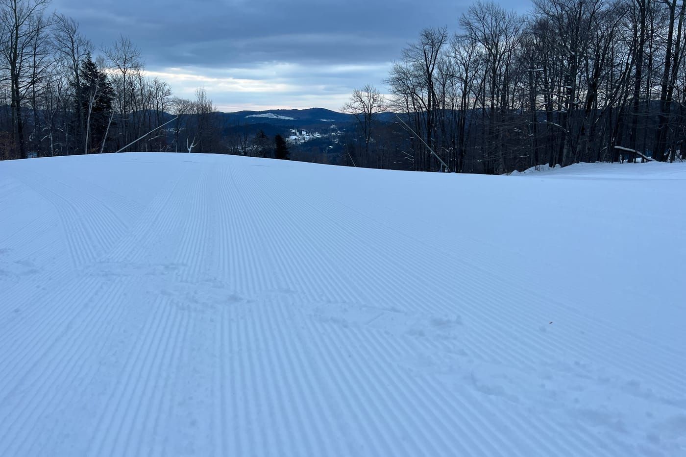 Freshly groomed corduroy on an Okemo trail at dawn, with the valley and hills beyond